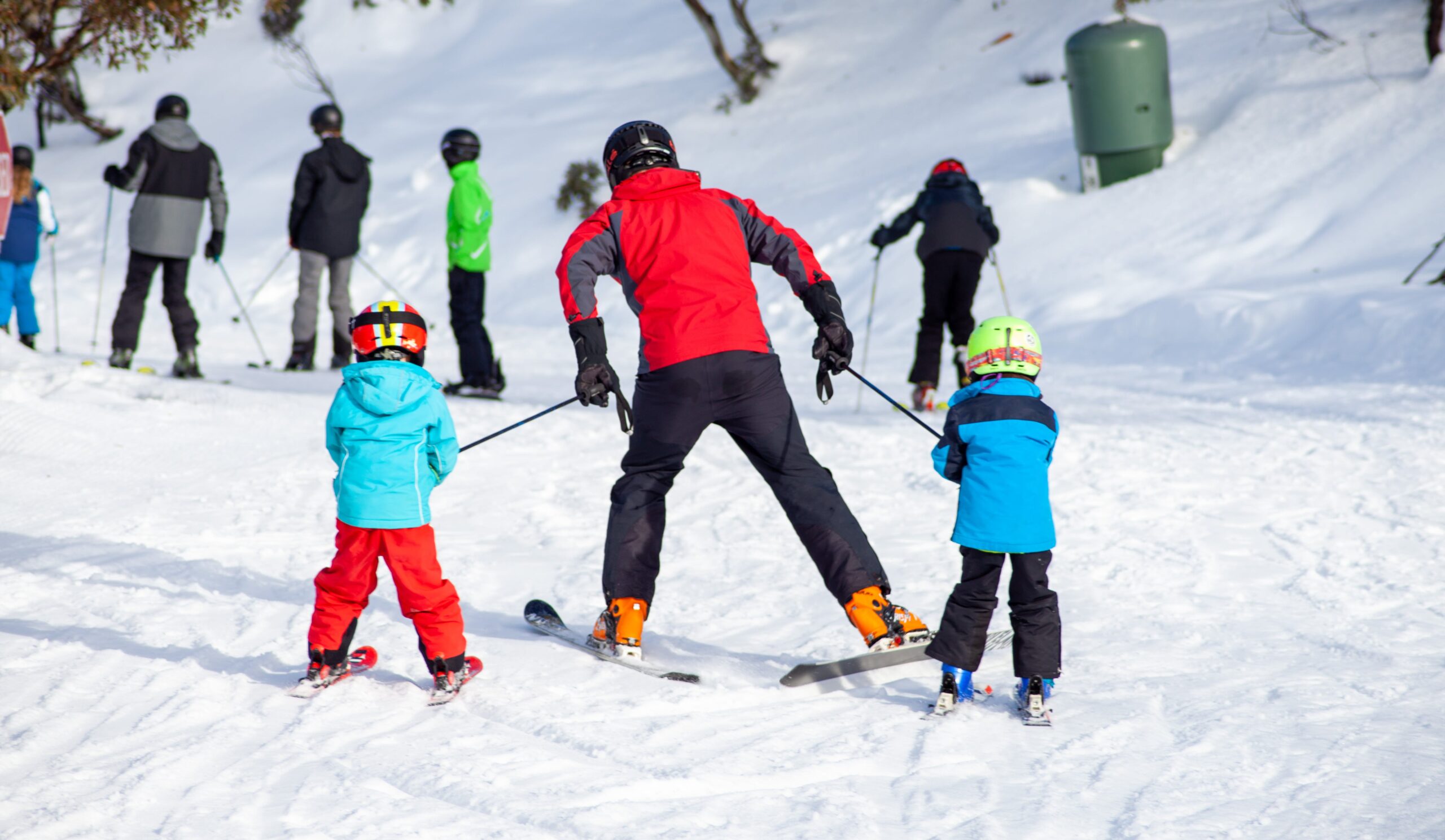 lyžovanie otec s deťmi na svahu
